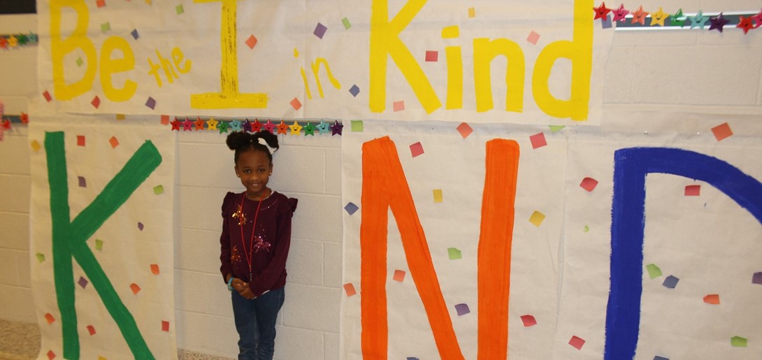 Student standing as the I in the word KIND