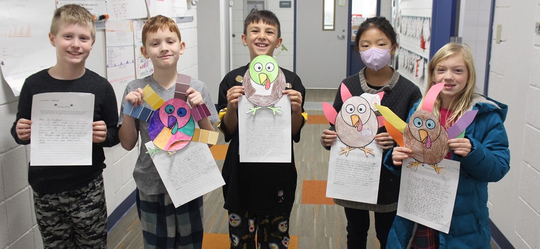 Students hold their essays and turkey drawings in their hands.