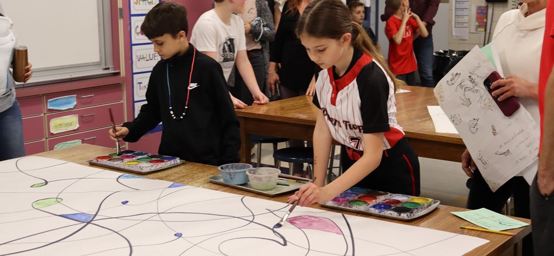 Students paint a mural in the art room as parents watch.