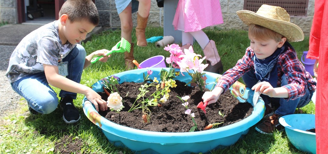 Students planting flowers and carrots in the dirt.