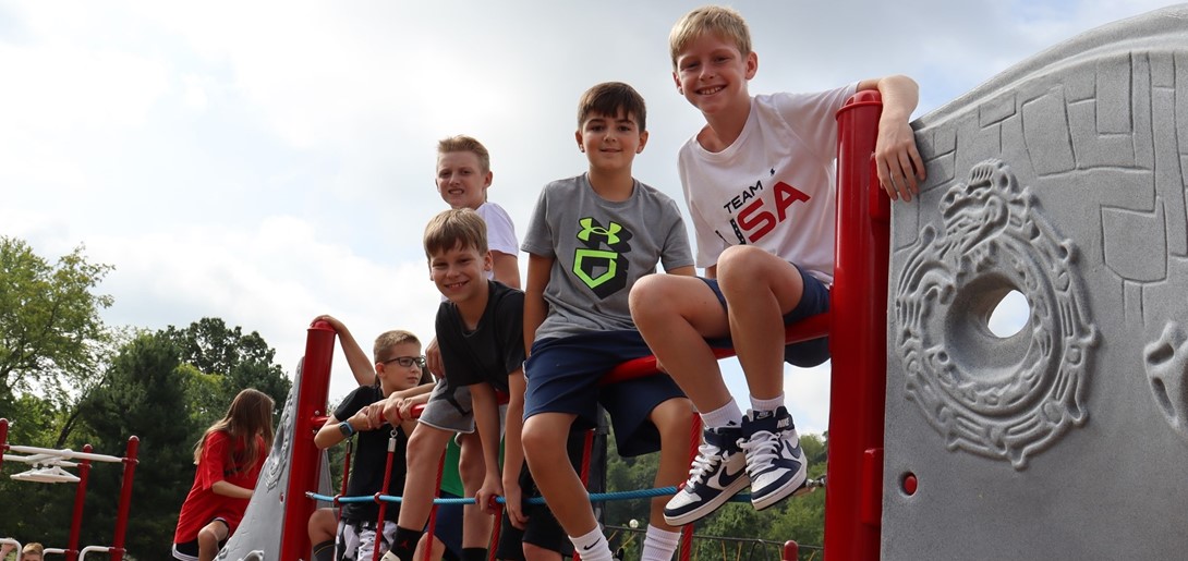 Boys sitting on top of climbing ropes on Playground.