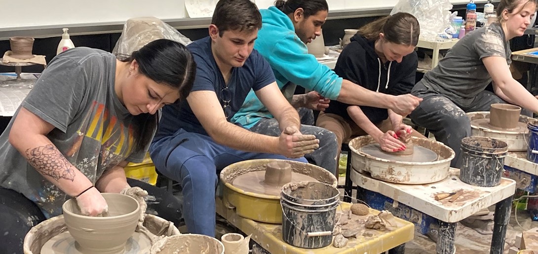 Students molding clay on the pottery wheel.