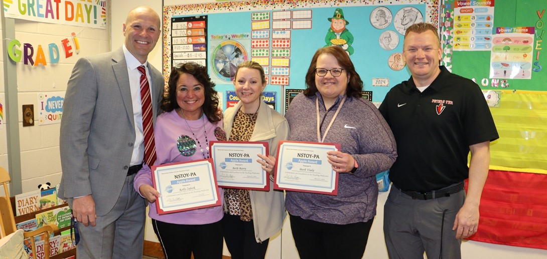 Teachers pose with administrators with their certificates.