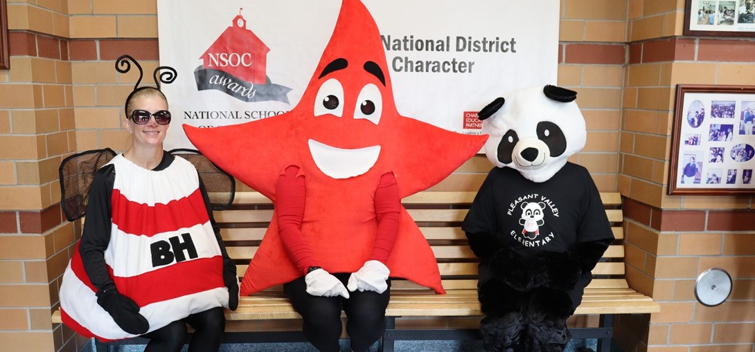 Three elementary mascots sitting on a bench.