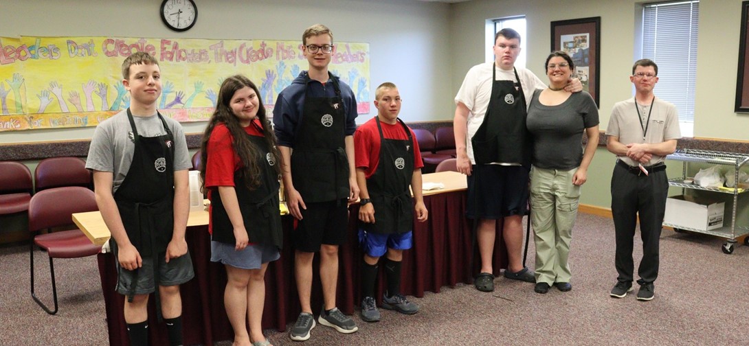Students in aprons standing in front of their coffee pots