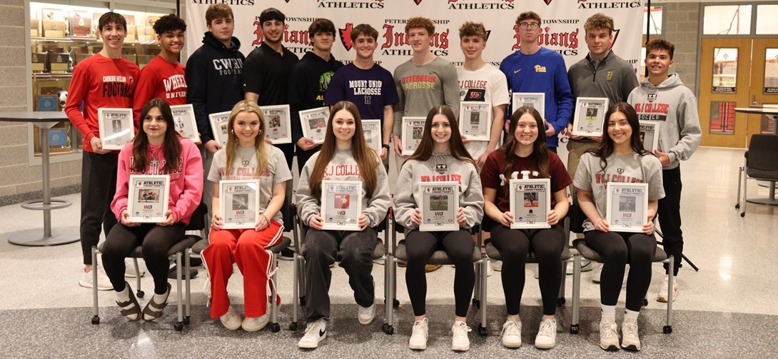 student athletes stand wearing shirts that say their college name on them
