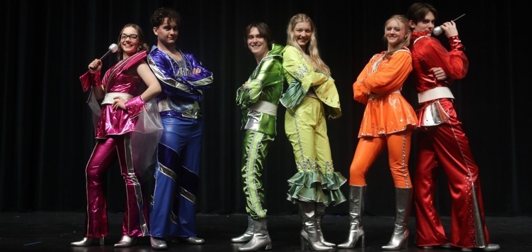 Students in costume on stage.