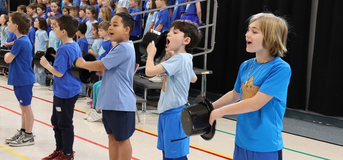 Students sing with top hats in hand.