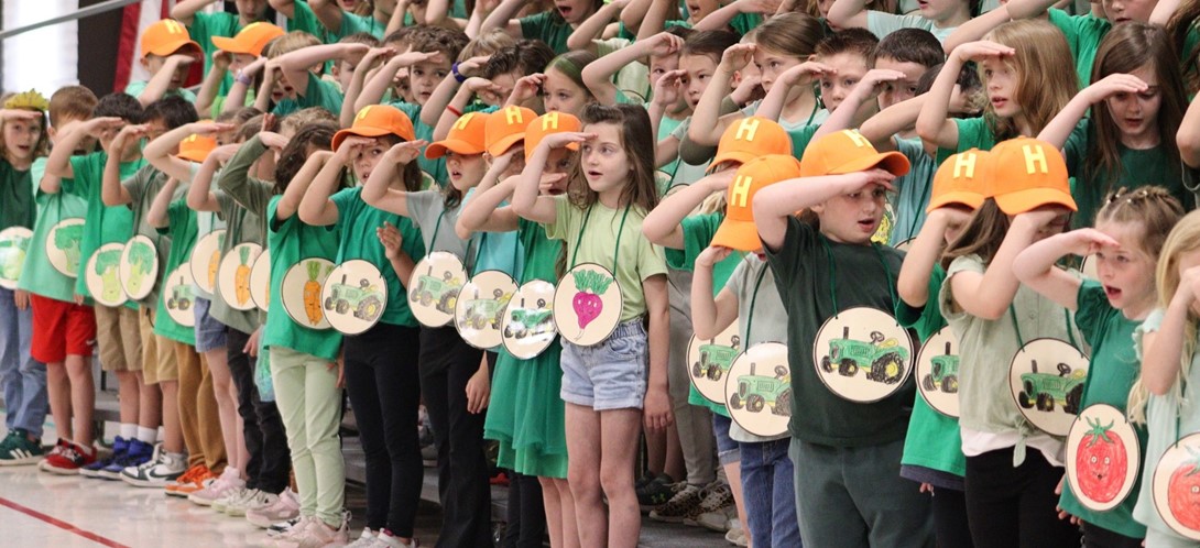 Students stand singing on the risers in the gym.
