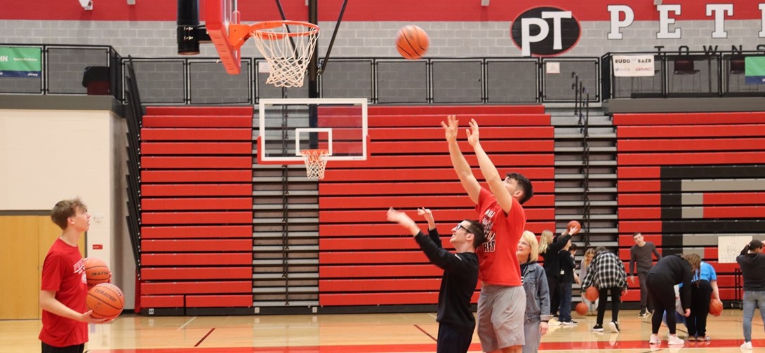 A students helps a student with special needs play baskeball.